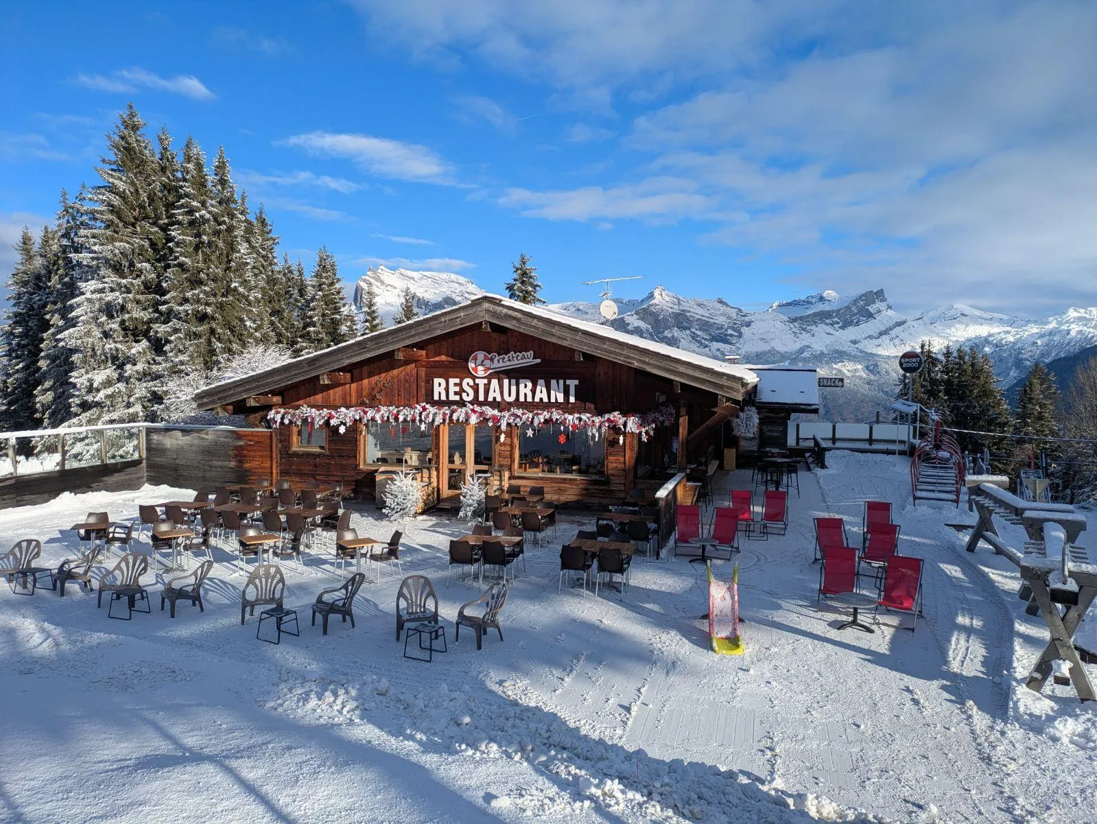 photo d'un restaurant d'altitude enneigé avec une terrasse sur les pistes et montagnes