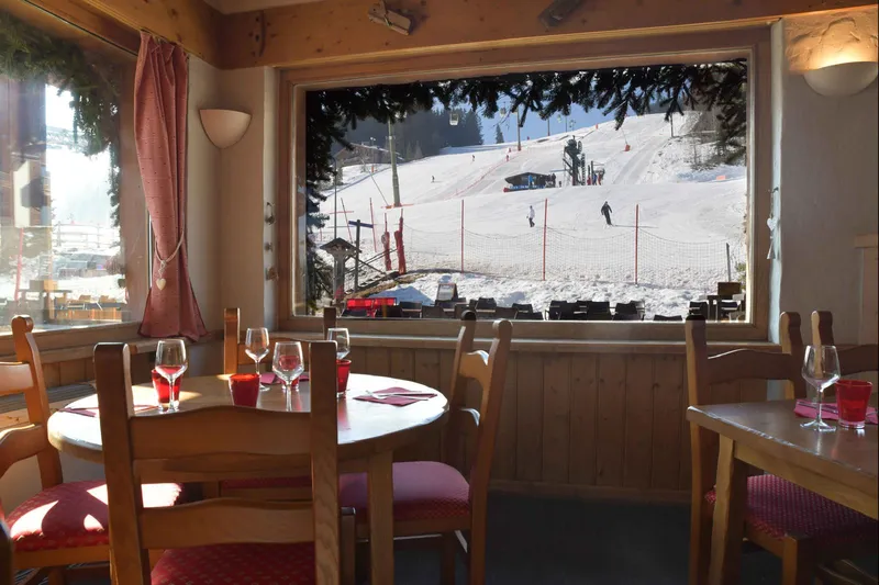 Salle intérieure du restaurant avec baies vitrées vue sur les pistes